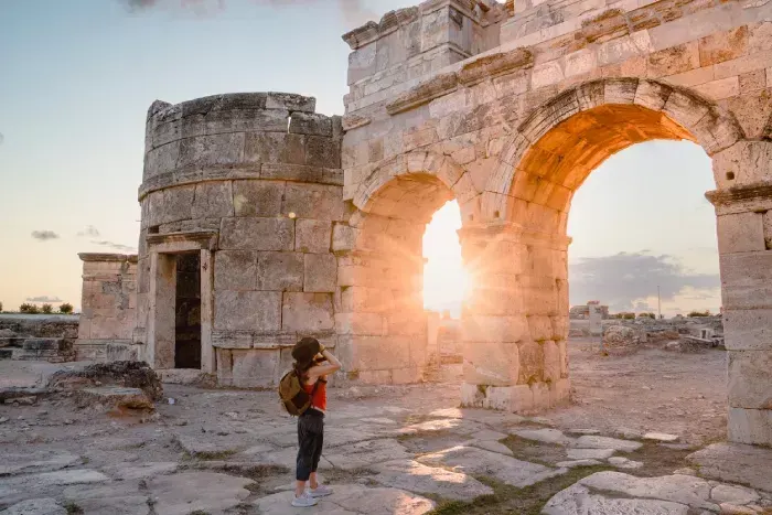  Tourist girl is taking photos of the Frontinus Gate in ancient ruins in Hierapolis 