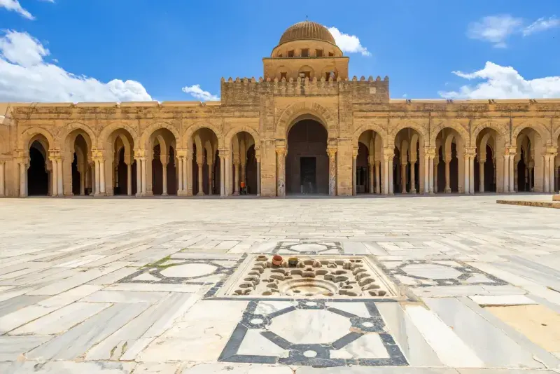 Dome, yard and columns of the Great Mosque of Uqba with clouds in the blue sky, Kairouan