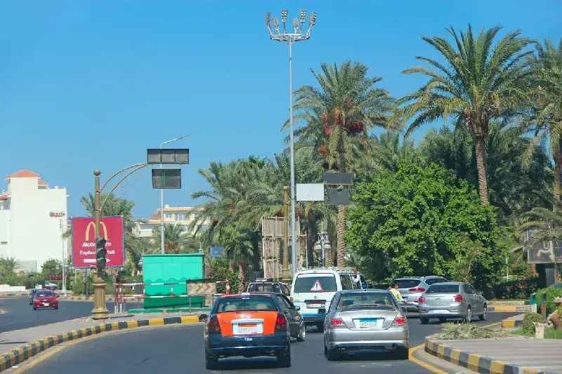 Stadtpanorama von Hurghada mit Straßenbahnen zwischen den Gebäuden. Eine moderne Stadt mit Autos auf der Schnellstraße. Transport und Verkehr auf der Stadtautobahn in Hurghada – eine belebte Straße in einer ägyptischen Stadt.