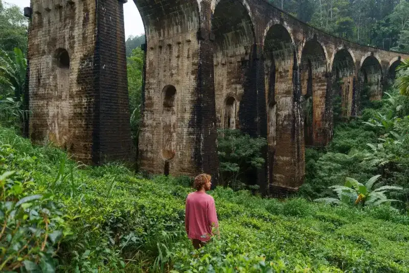 Un hombre sereno contempla la vista panorámica del Puente de los Nueve Arcos en Ella, Sri Lanka.
