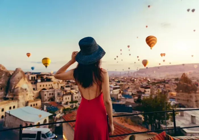 Beautiful asian woman watching colorful hot air balloons flying over the valley at Cappadocia, Turkey