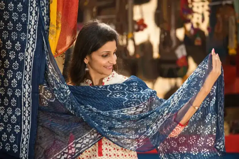 Mujeres indias felices comprando bufandas en un mercado callejero.