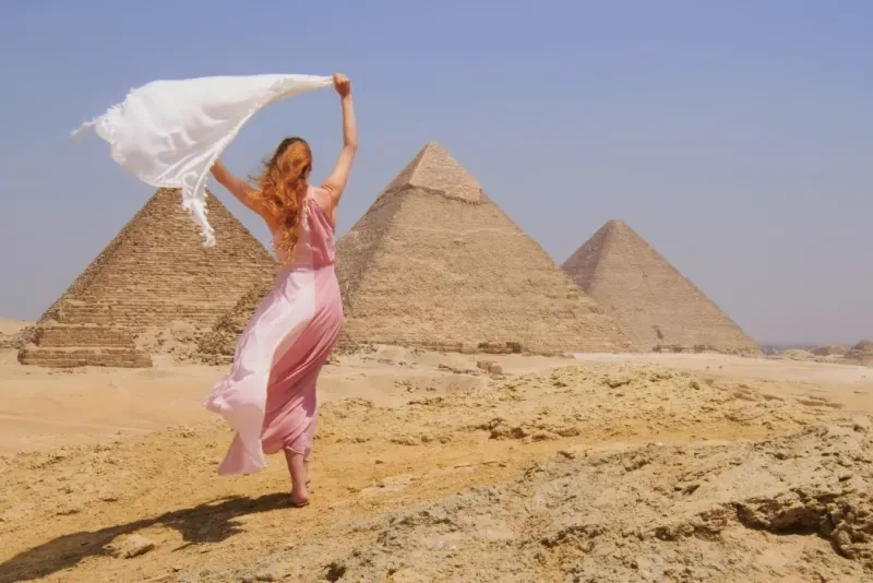 Donna con velo bianco al vento davanti alle Piramidi di Giza