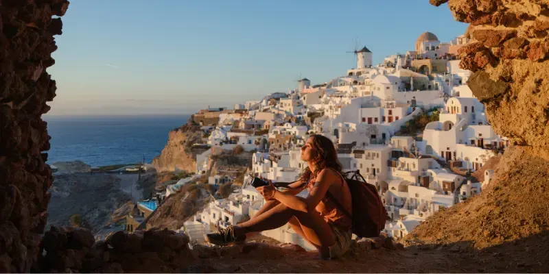 Mujer con cámara mirando con asombro en Oia, Santorini.
