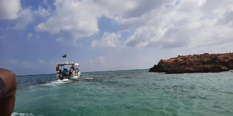 Embarcación navegando junto a una isla rocosa del archipiélago de las Islas Farasan en el mar Rojo, Arabia Saudita.