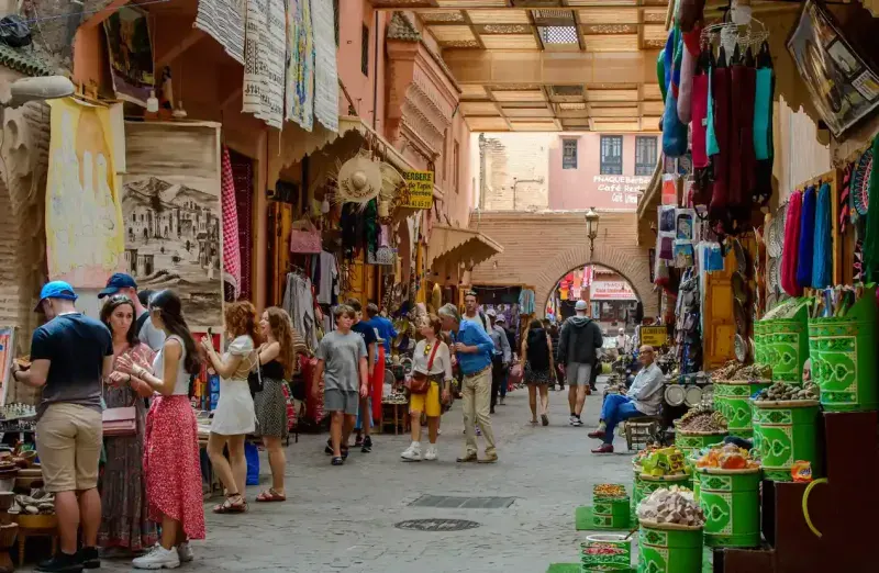 Tourists visiting Marrakech medina souks in a sunny day