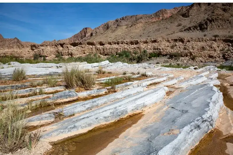 Slanted limestone benches in front of mountain range in Oman's Wadi Arbiyeen