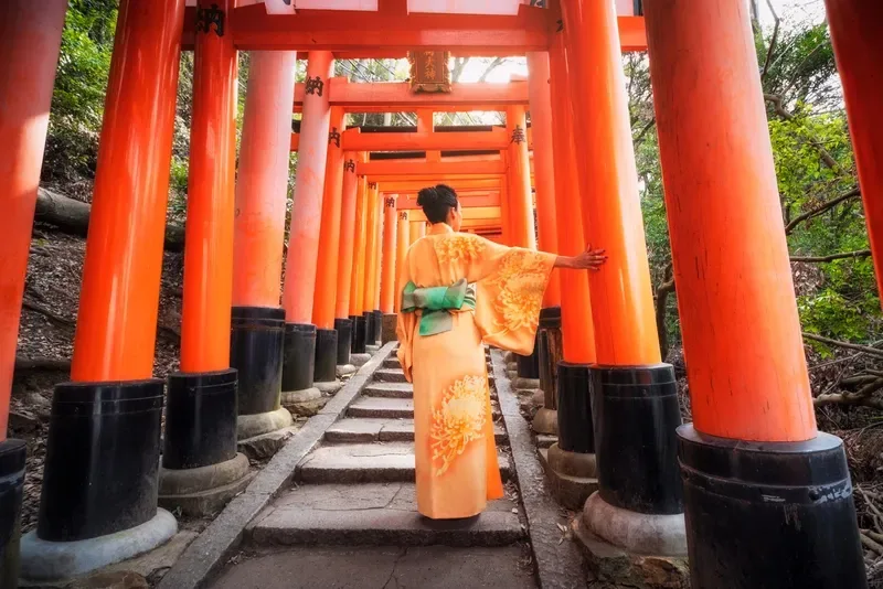 mulher-de-quimono-caminhando-entre-portoes-torii-no-santuario-fushimi-inari-kyoto