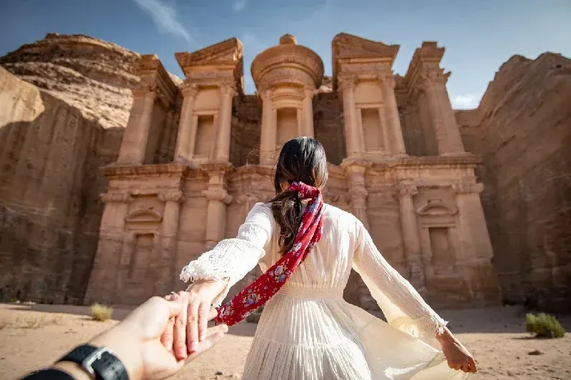 Woman in white dress holding her partner’s hand at Petra’s Al Deir monastery,