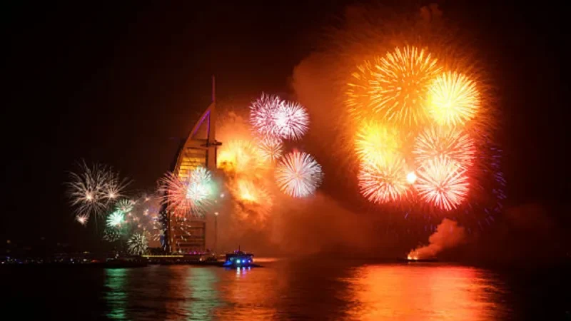 Spektakuläres Feuerwerk zur New Year's Eve am Jumeirah Beach in Dubai, mit bunten Explosionen am Himmel, die sich über dem Meer und der beleuchteten Küste spiegeln.