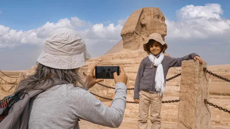 A woman Takes a photo of Her Son in Giza Pyramids