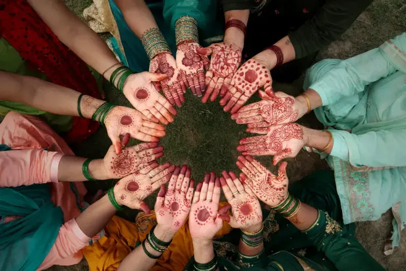 Grupo de mujeres indias irreconocibles mostrando sus manos con henna en el festival tradicional Teej, Haryali Teej (Hartalika Teej).