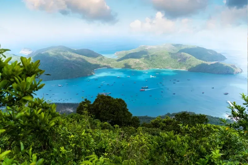 Blick auf den Ben Dam Hafen auf der Insel Con Dao mit blauem Meer, Himmel, Bergen und farbenfrohen Booten