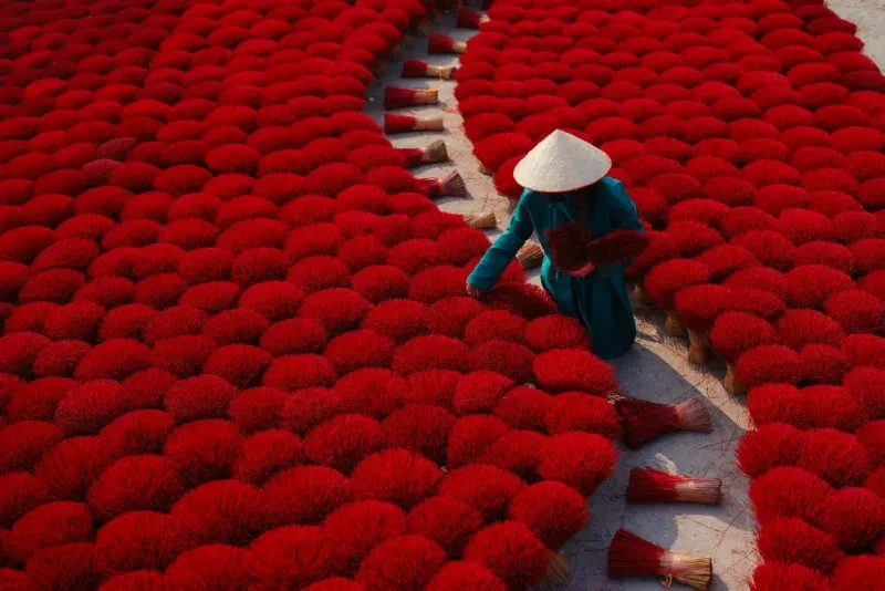 Mujer con vestido verde trabajando en una aldea de fabricación de incienso en Vietnam.