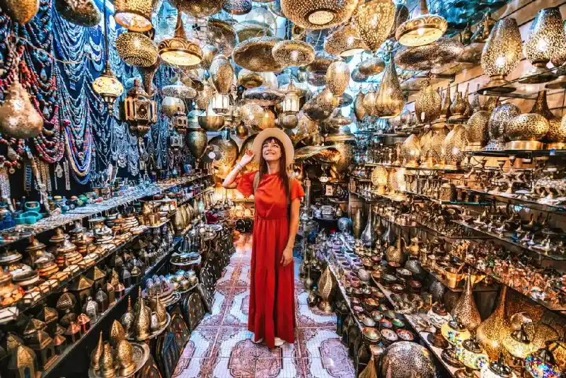 Mujer viajera visitando tienda de artesanía en cobre en Marrakech, Marruecos.