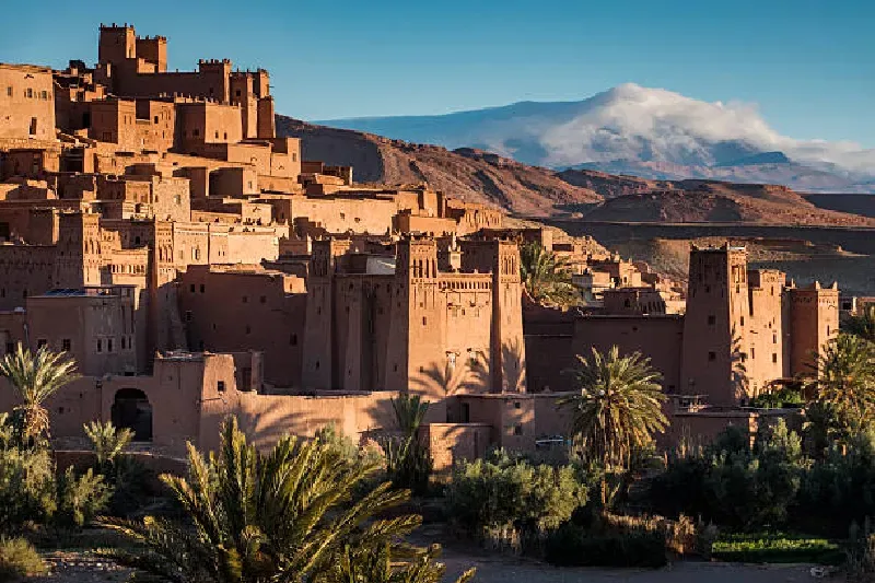 Blick auf das historische Lehmdorf Aït Benhaddou bei Sonnenuntergang in Marokko, warme Farben am Himmel