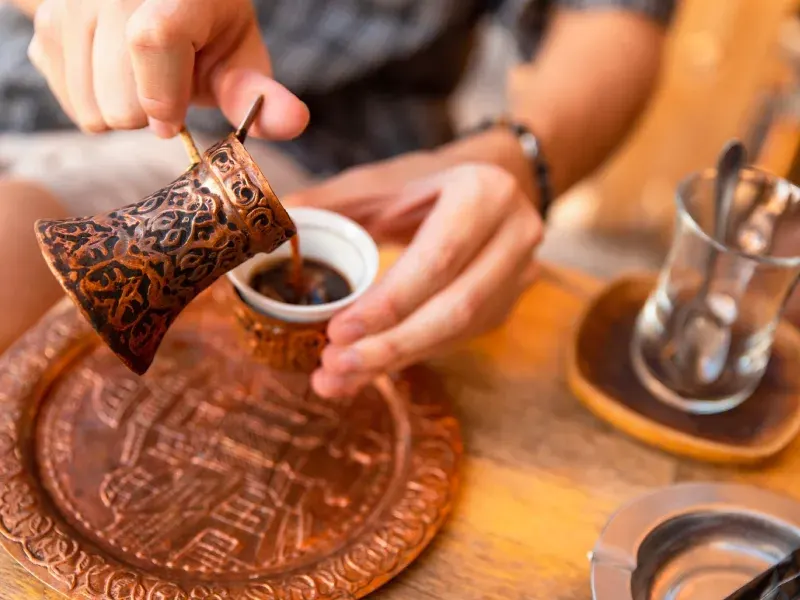 Caffè arabo tradizionale versato da un pentolino in rame