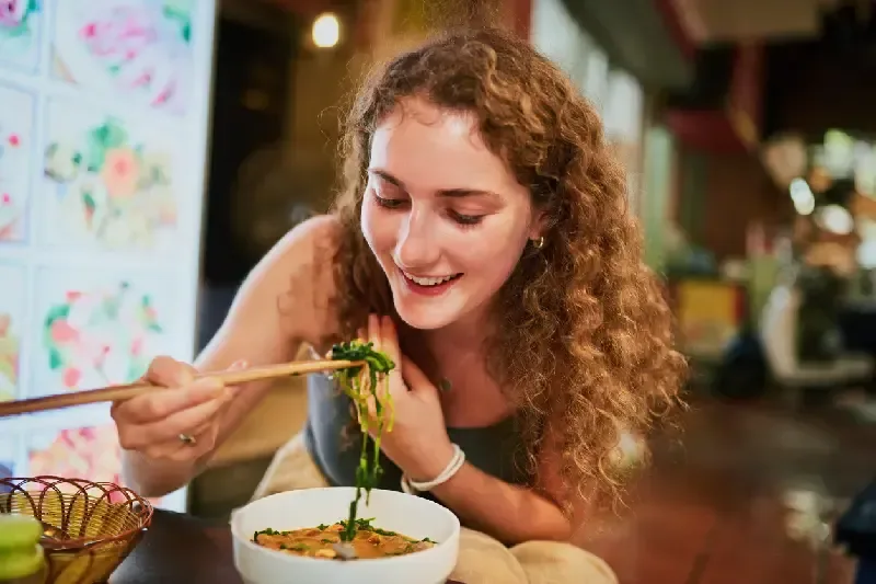  Young woman eating a bowl of Pho
