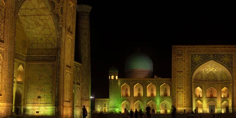 Piazza Registan con le madrase Tilla-Kari e Ulugh Beg illuminate di notte a Samarcanda, con le tre madrase
