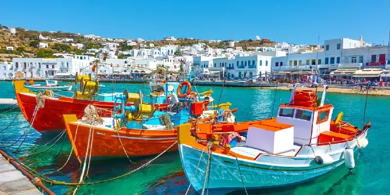 Puerto con antiguos barcos de pesca y el paseo marítimo en la isla de Mykonos, Grecia.