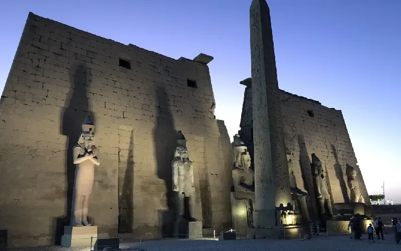 Temple de Louxor illuminé au crépuscule avec son obélisque et ses statues