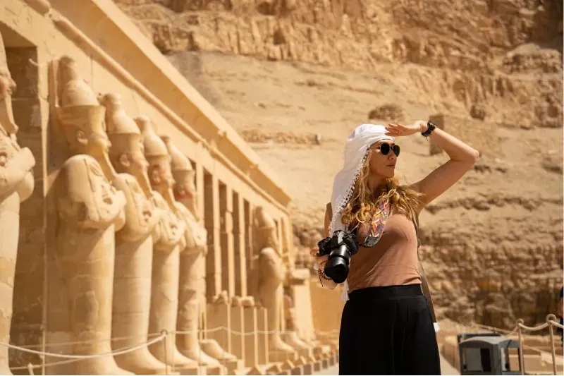 Donna in viaggio in Egitto mentre scatta foto al maestoso Tempio di Hatshepsut.