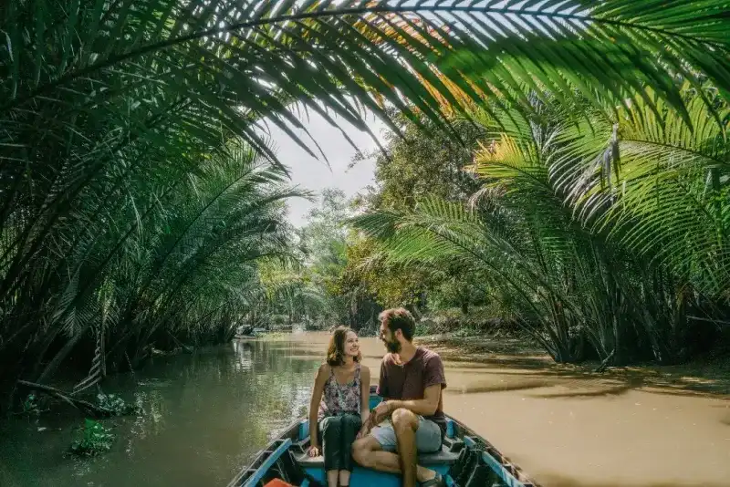 Joven caucásica viajando en barco por el delta del Mekong en Vietnam.