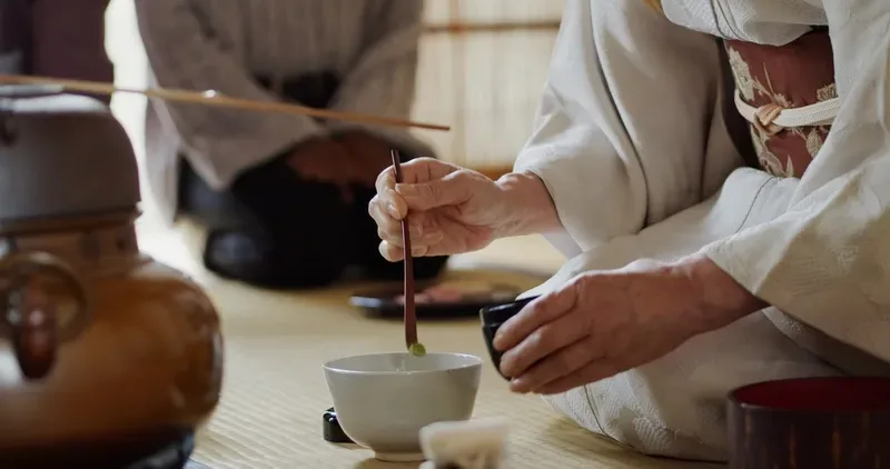 maos-preparando-matcha-com-colher-de-bambu-em-tigela-de-ceramica-durante-cerimonia-do-cha