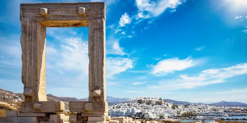 La famosa puerta de la isla de Naxos, llamada Portara del templo de Apolo, frente a las casas encaladas de la ciudad, Grecia.