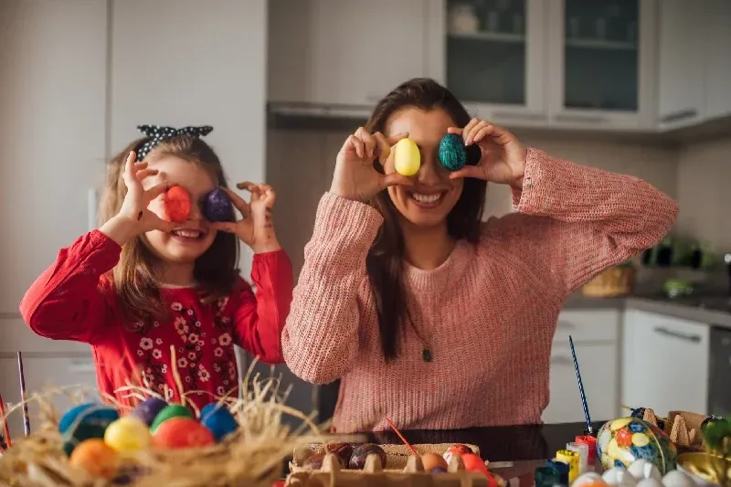 Glückliches Mädchen, das Spaß mit Mama und Ostereiern hat