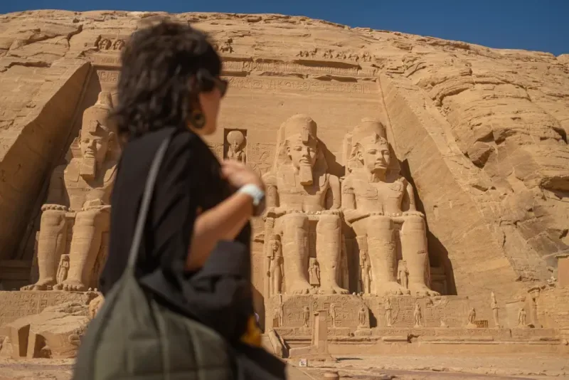 Turista davanti alle statue colossali di Ramses II al tempio di Abu Simbel