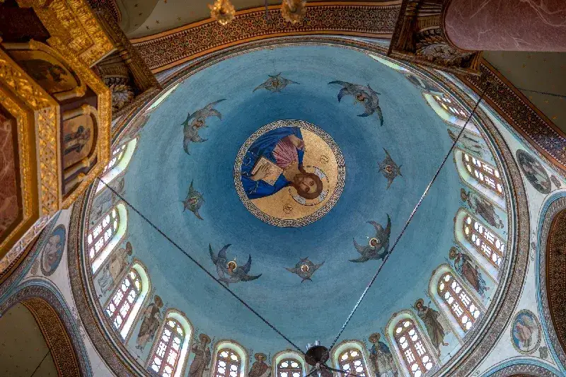 Blick von unten in die bemalte Kuppel einer orthodoxen Kirche mit goldenem Christus-Mosaik und Engelsfiguren