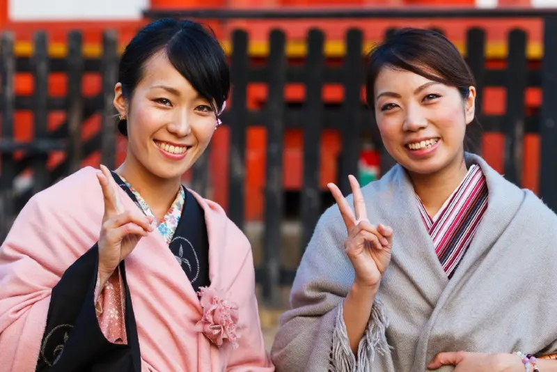 Due ragazze giapponesi in kimono che fanno il segno della pace