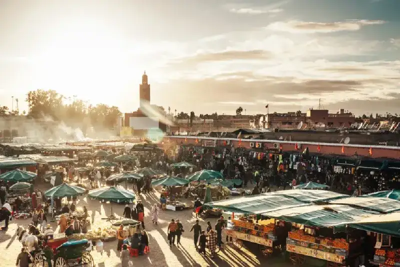 La famosa plaza Jemaa el-Fna de Marrakech al atardecer, con la mezquita Koutoubia al fondo.