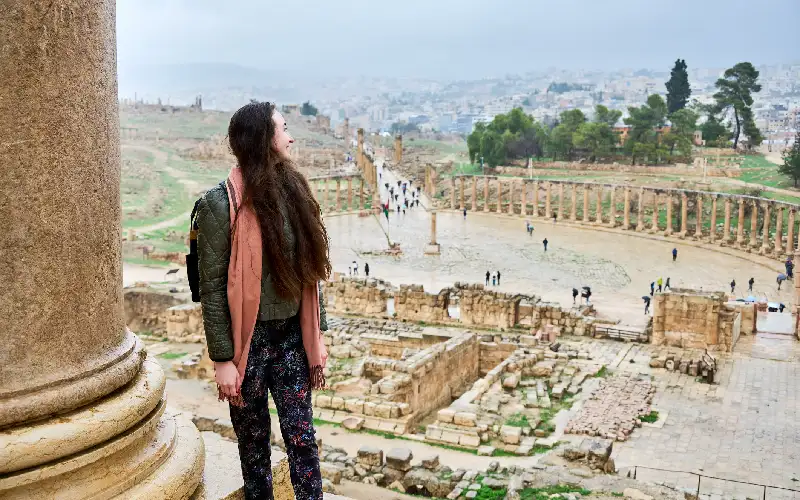 Woman admires sweeping view of ancient Oval Plaza and Roman colonnades in Jerash, Jordan