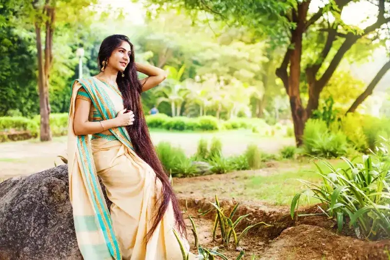 Hermosa mujer india con cabello muy largo vestida con un sari en un parque.