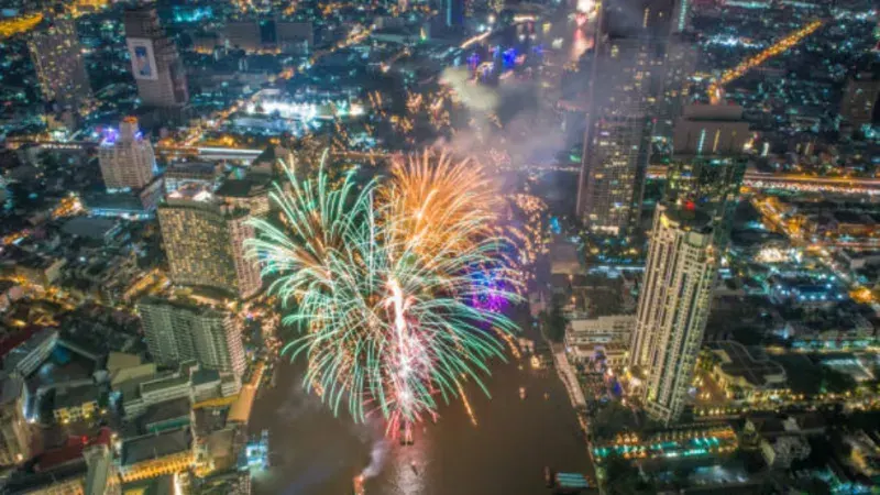Festliche Feierlichkeiten zum New Year's Eve in Bangkok, Thailand, mit farbenfrohem Feuerwerk über der Skyline, beleuchteten Tempeln und Menschenmengen, die das neue Jahr begrüßen.