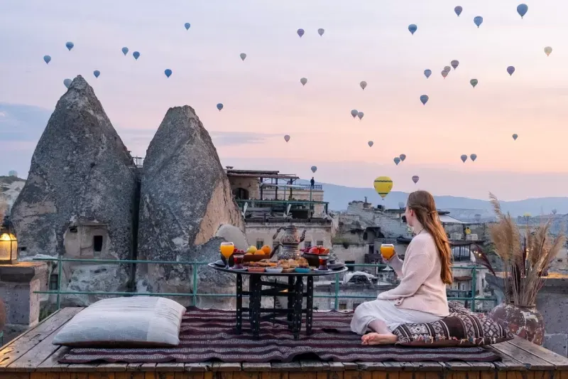 A woman enjoys the dreamy balloon-filled sky from her Cappadocia stay.