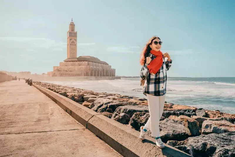 Young woman walking on the breakwater near Hassan II Mosque in Casablanca, Morocco