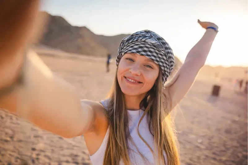 Giovane donna bionda si scatta dei selfie nel deserto. È in vacanza in Egitto.