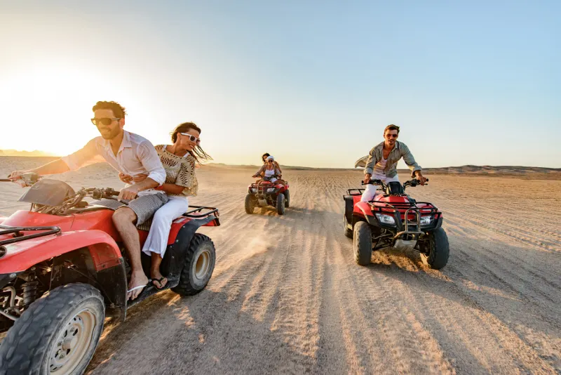 Happy friends driving quads in the desert at sunset, Best Time to Visit Egypt