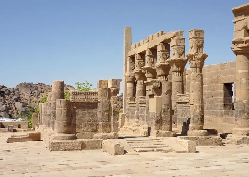 Touriste avec chapeau et bouteille d’eau devant le temple de Philae à Assouan