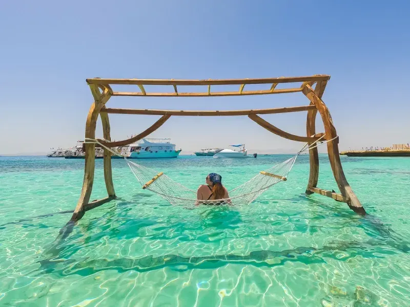 Una splendida giovane donna sdraiata su un'amaca sulla spiaggia dell'isola paradisiaca in Egitto.