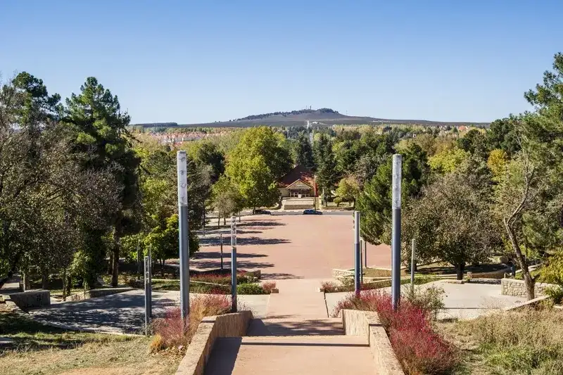 alameda-arborizada-em-ifrane-com-pavilhao-ao-fundo-e-colinas-no-horizonte