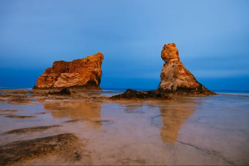 Die berühmten Felsen des Cleopatra Beach bei Marsa Matruh in Ägypten bei Nacht. Die markanten Felsformationen an der Mittelmeerküste spiegeln sich im ruhigen Wasser und schaffen eine stimmungsvolle Atmosphäre unter dem Nachthimmel.