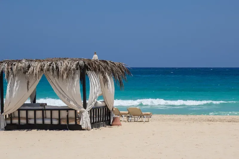 Holzsteg zur markanten Felsformation am Cleopatra Beach bei Marsa Matruh in Ägypten. Die mediterrane Küste mit kristallklarem, türkisfarbenem Wasser und den natürlichen Felsen bietet eine malerische Kulisse.