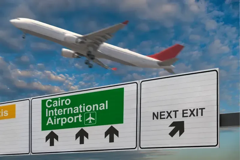 Schild des internationalen Flughafens Kairo mit startendem Flugzeug im Hintergrund