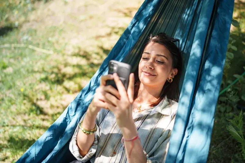 Young Woman Using Mobile Phone in Hammock