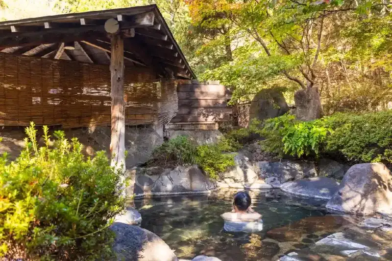 Una mujer relajándose en un baño onsen al aire libre
