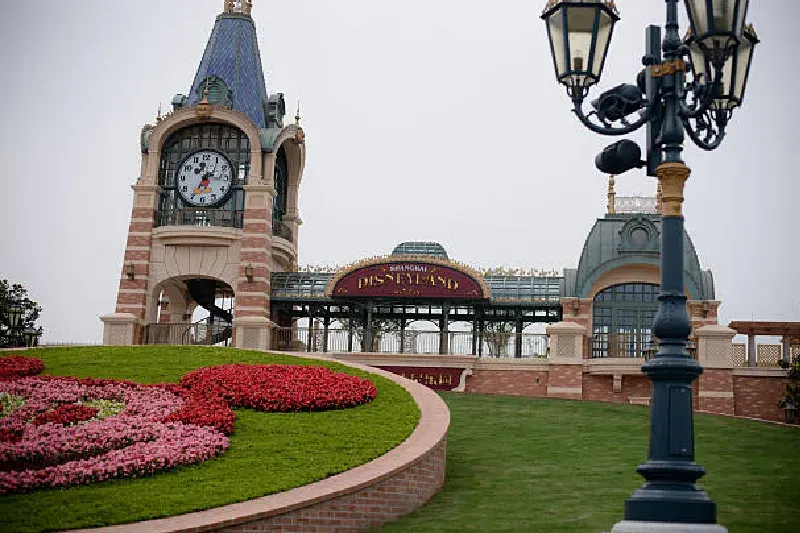 Der Haupteingang des Shanghai Disneyland Parks mit dem markanten Tor, Besuchern, die den Park betreten, und bunten Dekorationen im Hintergrund.